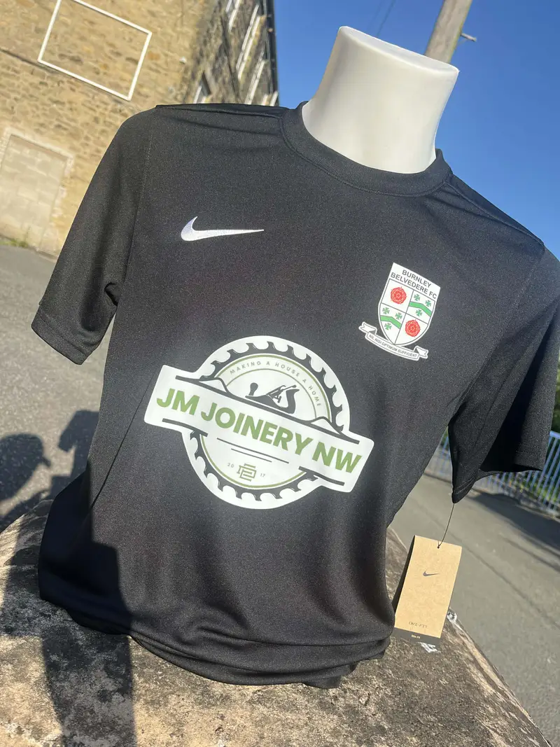 Black Nike training top carrying an embroidered football club crest and a printed JM Joinery NW sponsor logo